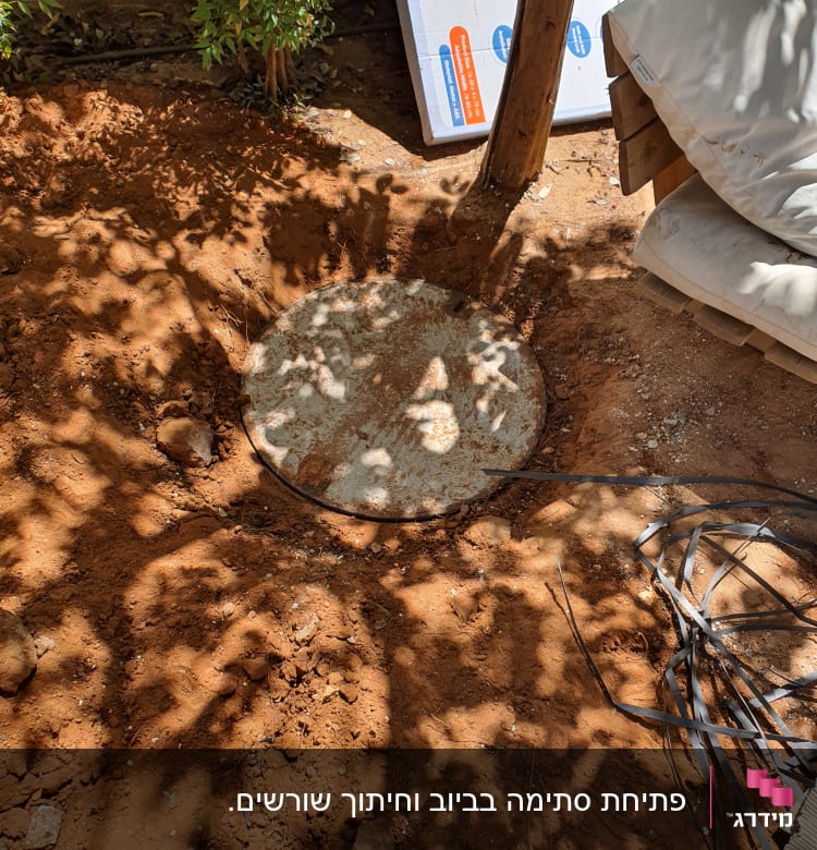 מכסה ביוב עגול באדמה עם צינורות פלסטיק